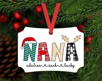 May include: A white Christmas ornament with the word "NANA" in colorful, festive lettering. The ornament features a Santa hat, reindeer antlers, and the names "adalinn", "zach", and "lucky" below. A red ribbon is attached for hanging.