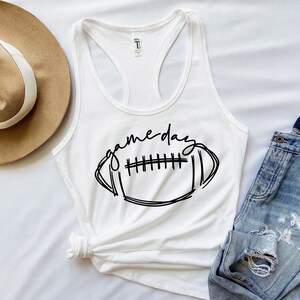 May include: White tank top with a black graphic of a football and the text "game day".
