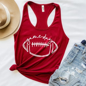 May include: A red tank top with a white graphic of a football and the text "game day".