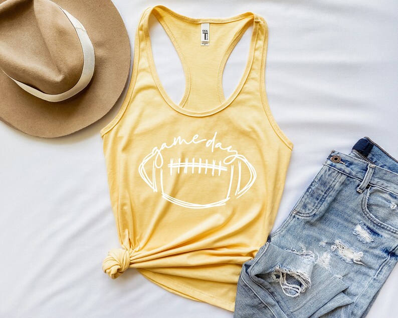 May include: A yellow tank top with a white outline of a football and the text "game day".