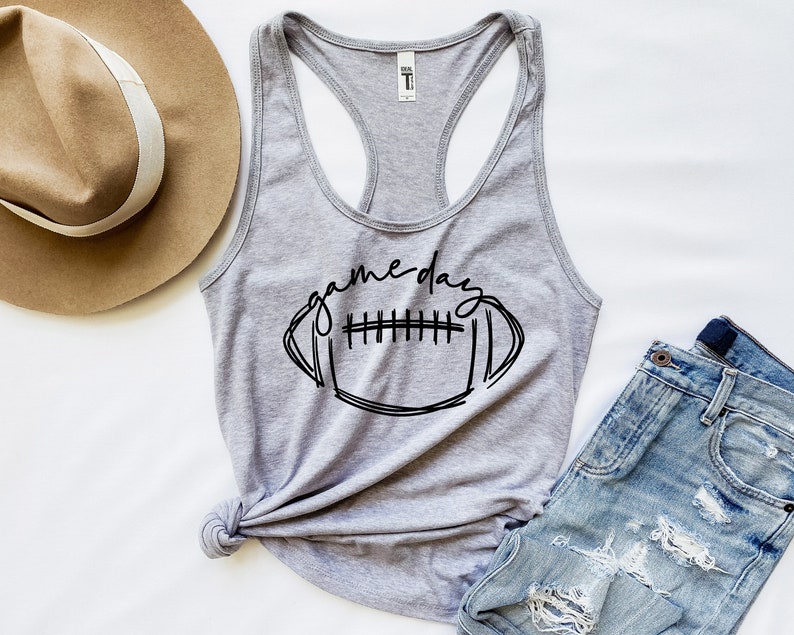 May include: Gray tank top with a black graphic of a football and the text "game day".