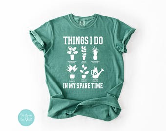 May include: A teal green t-shirt with white text that reads "Things I do in my spare time". The text is surrounded by illustrations of plants and gardening tools.