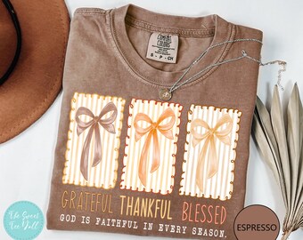 May include: Espresso-colored t-shirt with three bow illustrations in shades of brown and orange. The shirt features the words "Grateful, Thankful, Blessed" and "God is Faithful in Every Season."