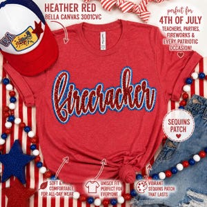 以下が含まれることがあります： 赤と青のスパンコールで「firecracker」の文字が入った、ヘザーレッドのBella Canvas Tシャツ。このシャツはユニセックスで、7月4日に最適です。赤、白、青の野球帽が左上にあります。