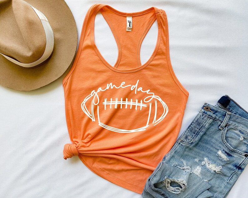 May include: Orange tank top with a white graphic of a football and the text "game day".