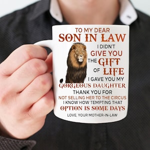 May include: White ceramic coffee mug with a brown lion illustration and text that reads "To my dear son in law I didn't give you the gift of life I gave you my gorgeous daughter Thank you for not selling her to the circus I know how tempting that option is some days Love, your mother-in-law"