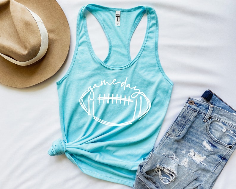 May include: A light blue tank top with a white graphic of a football and the text "game day".
