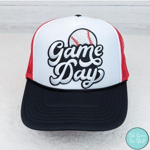 Könnte beinhalten: Weiße und rote Trucker-Kappe mit einem gestickten Baseball in Schwarz und Weiß und dem Text "Game Day".