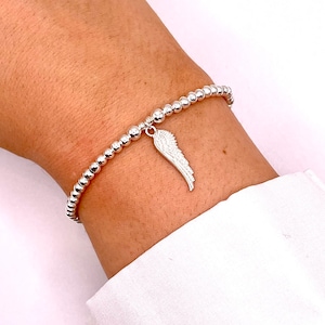 May include: A silver beaded bracelet with a silver angel wing charm.
