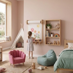 May include: A wall-mounted wooden paper roll holder with a drawing of a sun and flowers, featuring a built-in shelf with colored pencils. The setup includes a wooden bookshelf, a pink scalloped armchair, and a green beanbag chair.
