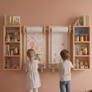May include: A wall-mounted wooden art station featuring two vertical paper roll dispensers, two integrated shelves for supplies, and two flanking bookcases filled with children's books, toys, and colorful art materials.