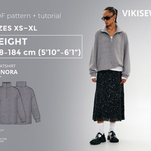 May include: A gray sweatshirt with a zippered collar and long sleeves. The sweatshirt is called "Annora" and is available in sizes XS-XL. The model is 5'10"-6'1" tall. The pattern is a PDF download and includes a tutorial.