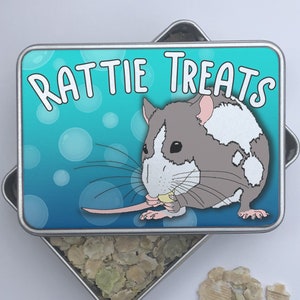 May include: A blue and green metal tin with a cartoon rat eating a treat. The tin says "Rattie Treats" on the lid. The tin is open and filled with small, green and brown treats.