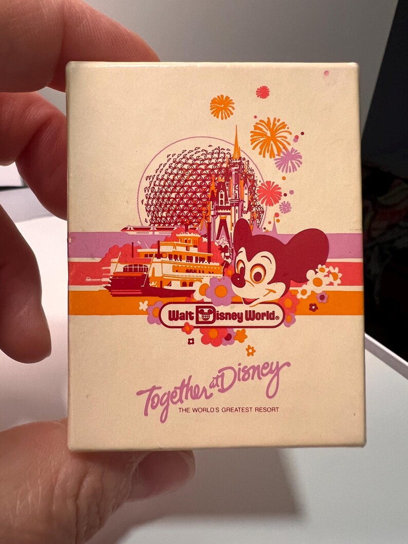May include: A rectangular off-white box featuring a colorful graphic of Walt Disney World landmarks, including a castle, a geodesic dome, a riverboat, and Mickey Mouse. The text reads Walt Disney World, Together at Disney, and The World's Greatest Resort.
