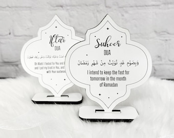 May include: Two white wooden signs shaped like a mosque dome with black text. The sign on the left says "Iftar DUA" and includes an Arabic prayer. The sign on the right says "Suhoor DUA" and includes an Arabic prayer and the English translation "I intend to keep the fast for tomorrow in the month of Ramadan."