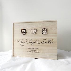 May include: A wooden keepsake box with a lion, elephant, and tiger design. The box is engraved with the name "Kian Singh Badhan", the date "October 22, 2022", the time "12:06 PM", and the baby's weight and length: "7 lbs 9 oz 20 inches".