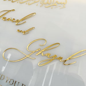 May include: A white background with gold lettering. The text reads "And you in pairs" and "7:8" in a smaller font. The names "Taimur" and "Shayal" are written in cursive.
