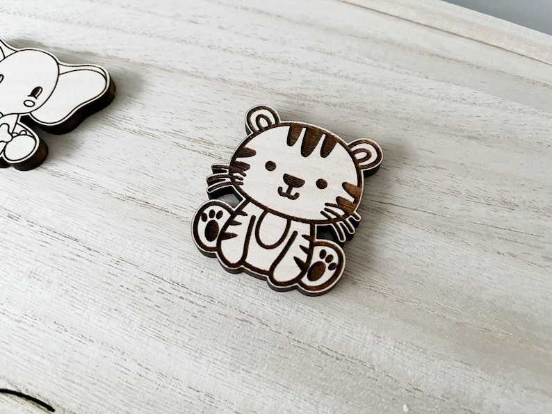 May include: A wooden cutout of a tiger with black stripes. The tiger is sitting with its paws in front of it and has a friendly expression on its face.