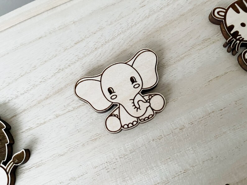 May include: A white wooden elephant with a cute cartoon face and big ears. The elephant is holding a small ball in its trunk.