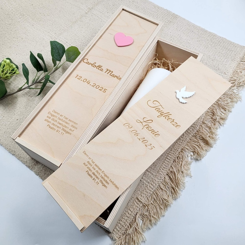 Zwei Taufkerzenbox mit Schiebedeckel mit Gravur: Name, Datum, persönlicher Widmung. Auf der Oberseite befindet sich ein 3D Motiv mit weißer Taube und eine Box mit rosa Herz