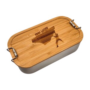 Könnte beinhalten: Eine rechteckige Bambus-Lunchbox mit einem Edelstahl-Innenraum. Der Deckel ist mit einem Laser-gravierten Design einer Person beim Klettern an einer Felswand mit dem Text "Finn Lasch" über dem Design versehen.