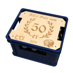 May include: A blue plastic crate with a wooden lid. The lid has a laser-engraved design with a laurel wreath, the number 50, the word "er", and the year 2021. The text "Alles Gute zum" is also engraved on the lid.