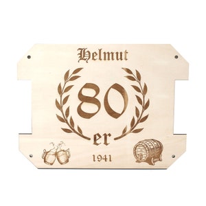 May include: A wooden sign with the text "Helmut 80 er 1941" engraved on it. The sign is decorated with a laurel wreath, two beer mugs, and a barrel.