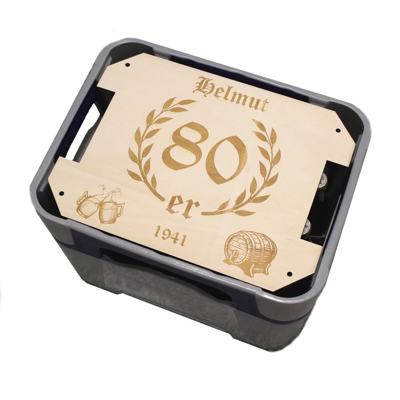 May include: A wooden crate with a personalized inscription for an 80th birthday. The inscription reads "Helmut 80 er 1941" with a laurel wreath and a beer stein graphic.