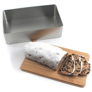 Geöffnete Keksdose aus Metall mit einem Bambusdeckel, der als Schneidbrett verwendet wird. Auf dem Schneidbrett liegt ein angeschnittener Stollen, perfekt zur Zubereitung und Aufbewahrung von Weihnachtsgebäck.