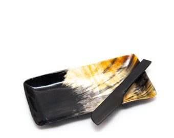 May include: A rectangular serving tray with a black and amber horn design, paired with a matching black butter knife. The tray has a glossy finish and is set against a white background. The tray measures approximately 10 inches long.