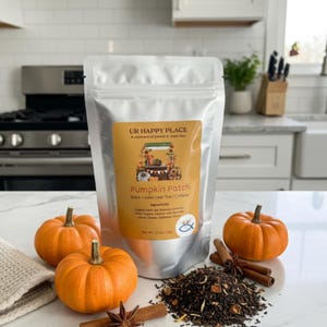 May include: A silver pouch of "Pumpkin Patch" loose leaf tea with a label that reads "UR HAPPY PLACE". The image includes three small orange pumpkins, cinnamon sticks, and star anise. The tea is displayed on a white surface.