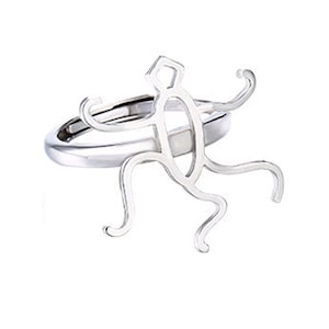 Puede incluir: Un anillo de plata con un diseño estilizado de una persona con los brazos en alto.