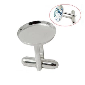 May include: Silver cufflinks with a round, blank, silver-toned bezel. The cufflinks are designed to hold a small, round, flat, decorative item, such as a cameo or a piece of jewelry.