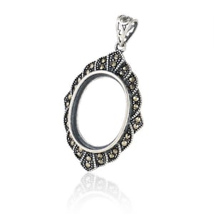 May include: Silver oval pendant with a marcasite setting. The pendant is designed to hold a cameo or other small object.
