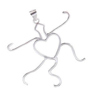 Può includere: Collana con ciondolo in argento con una figura stilizzata con un cuore al centro. La figura è realizzata in filo sottile e ha un design semplice e astratto.
