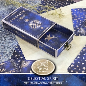 May include: A blue tarot card box with celestial designs, including stars, a sun, and a checkered sphere. The box is open, revealing a drawer with a pegasus illustration. Text on the box reads "CELESTIAL TAROT".