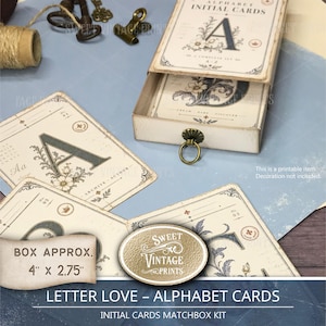 Puede incluir: Un conjunto de tarjetas con iniciales del alfabeto que presentan ilustraciones florales decorativas y tipografía. Las tarjetas se guardan en una caja rectangular tipo cerilla con un anillo de metal. La caja mide aproximadamente 10,16 cm por 6,99 cm.