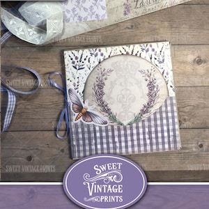May include: A purple and white junk journal folio with a lavender theme. The folio features a round window with a floral design and a butterfly. The text "Vintage Lavender Folio" and "Junk Journal Folio" is printed on the front.