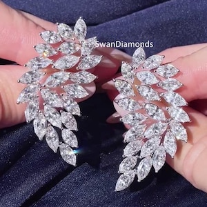 May include: A pair of silver earrings with a cluster of marquise-shaped diamonds in a leaf design. The earrings are called "SwanDiamonds".
