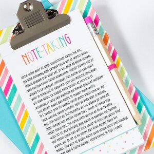 May include: A white clipboard with the words "NOTE-TAKING" in colorful letters at the top. The clipboard has lined paper and a pink pencil is sticking out of the top.