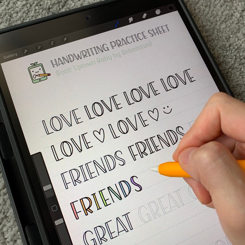 May include: A digital tablet screen displaying a handwriting practice sheet with the words "LOVE LOVE LOVE LOVE", "LOVE♡LOVE♡", "FRIENDS FRIENDS", "FRIENDS", and "GREAT GREAT" written in a cursive font. The words are written in black ink on a white background with lined paper.