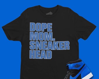 May include: Black t-shirt with blue text that reads "Dope Mom. Sneaker Head". A pair of black and blue sneakers are shown below the t-shirt.