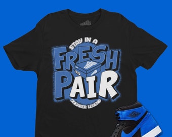 May include: Black t-shirt with a blue and white graphic that says "Stay in a Fresh Pair Sneaker Legend". A pair of blue and black sneakers are also pictured.