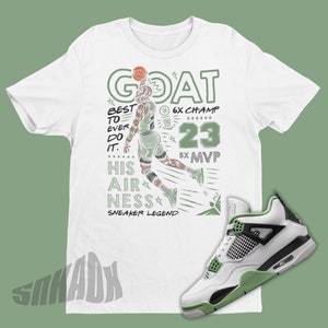 May include: White t-shirt with a green and black graphic of a basketball player with the text "GOAT", "BEST TO EVER DO IT", "HIS AIRNESS", "SNEAKER LEGEND", "6X CHAMP", "23", and "5X MVP". A pair of white, black, and green sneakers are shown in the bottom right corner of the image.