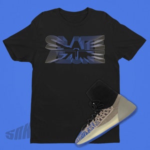 May include: A black t-shirt with a blue and white graphic that says "SLATE" on it. A pair of blue and white sneakers are placed on the t-shirt.