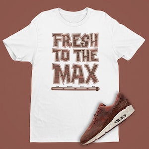 May include: White t-shirt with the text "FRESH TO THE MAX" in brown with a wood grain pattern. The text is accompanied by a progress bar labeled "LOW", "MEDIUM", "HIGH", and "MAX". A brown and white sneaker with a wood grain pattern is shown below the t-shirt.