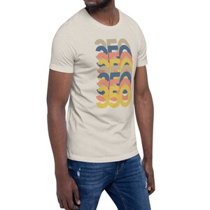May include: A beige t-shirt with a graphic design of the number 360 in a retro style with overlapping layers of yellow, orange, pink, and blue.
