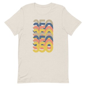 May include: A beige t-shirt with a graphic design of the number 350 repeated in a stacked, layered pattern. The numbers are in shades of yellow, orange, pink, and blue.