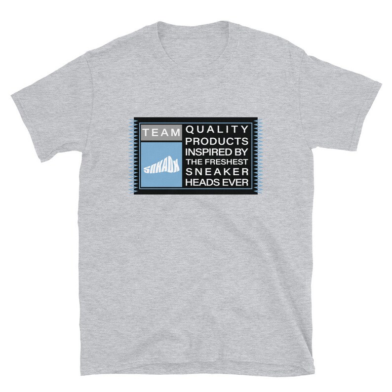 K&ouml;nnte beinhalten: Graues T-Shirt mit einer rechteckigen Grafik in Schwarz und Blau, auf der "TEAM QUALITY PRODUCTS INSPIRED BY THE FRESHEST SNEAKER HEADS EVER" steht.