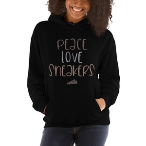 May include: Black hoodie with the text "Peace Love Sneakers" in white and brown lettering. The text is in a handwritten style.